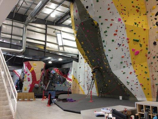 A setter putting up a new route on the lead-only wall. Some of the bouldering area in the background.