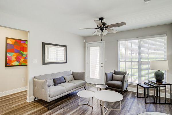 Living room area with ceiling fan and wood like floors