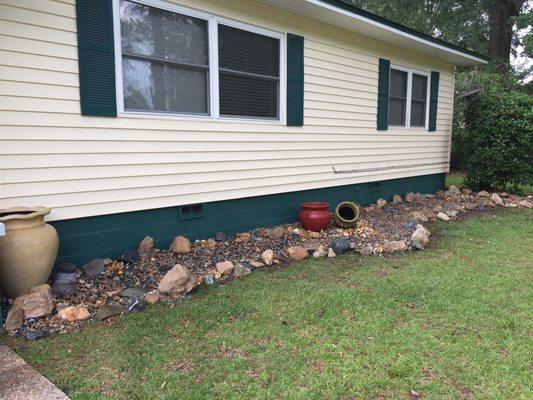 Customer wanted low maintenance rock bed with decorative pots installed along the front of her house.