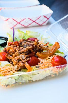 Pulled Pork Salad - Cherry Cola braised pulled pork served over mixed greens, cherry tomatoes, shredded cheese, and your choice of dressing