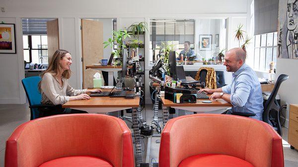 Two Oneupweb marketers talk strategy from their desks at the Oneupweb office.