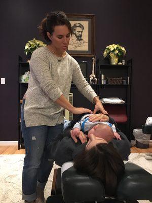 Dr. Lindsay adjusting a one month old baby while he's laying comfortably his mama