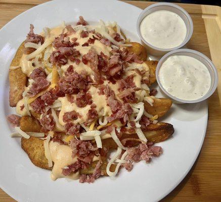 On Cue's Bacon Cheddar Wedges! with scratch made cheese sauce, grated cheeses, potato wedges, and lots of bacon crumbles!