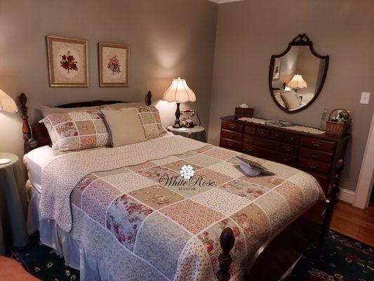 This queen room is quaint with muted colours for maximum calm. Dresser with mirror and wingback chair with footstool.