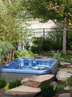 The family can enjoy this sunken hot tub flanked by natural stone, privacy cover, and gardens.