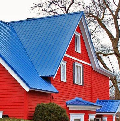 Striking blue metal roof on a bright red house, installed by our team.