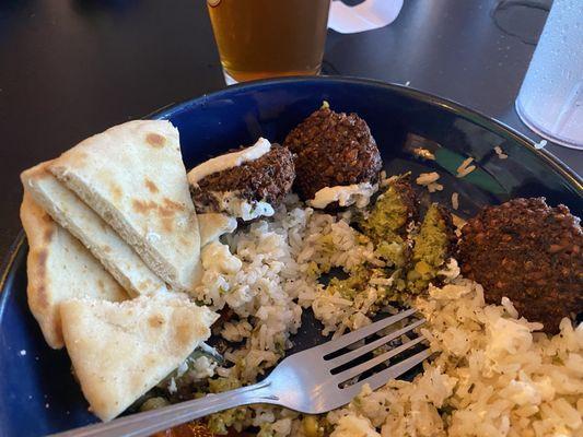 Falafel with pita, rice, sautéed vegetables, and tzatziki sauce.