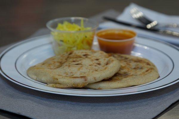 Two pupusas, served with pickled cabbage and freshly made tomato sauce