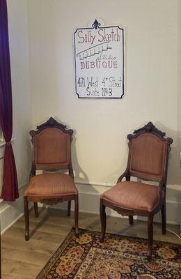 The two waiting Chairs for Guests under the Silly Sketch Upstairs Studio Dubuque logo.