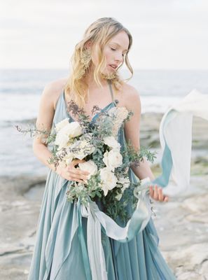 bride on the beach with white and green organic bouquet