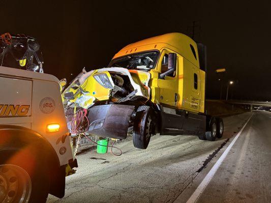 Towing away a wrecked semi truck from the interstate using a heavy duty wrecker