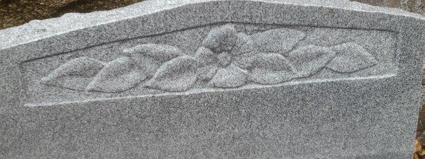 A newly carved flower on a granite memorial.