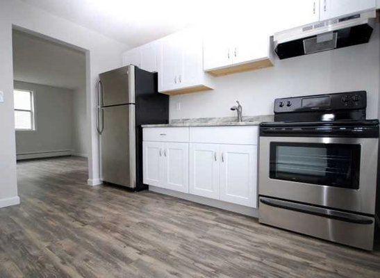 Each apartment's kitchen includes white shaker cabinetry, stainless steel appliances, and granite countertops.