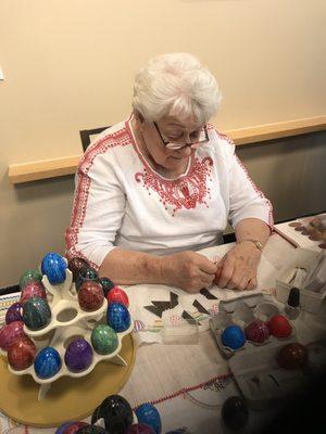 Busily carving designs in a stone egg with a straight edge blade.