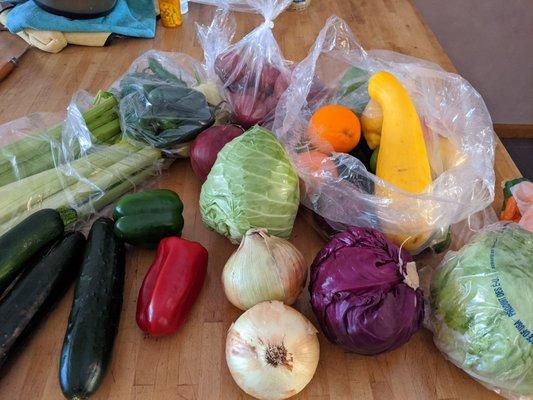 Produce box lots of goodies like peppers, cabbages, onions, cucumbers, fruits, limes, potatoes, and a big bag of chillies.