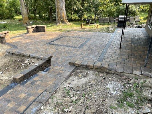 Patio, walkway and seating walls with inlay, doormat and bricks over pavement under balcony all done beautifully.