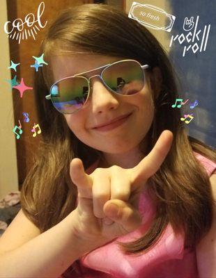 my kiddo sportin "designer" shades (probably from the dollar store) a "rock n roll" sign with her right hand, and a TON of swag