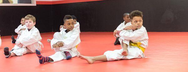 Kids jiu jitsu stretching out.