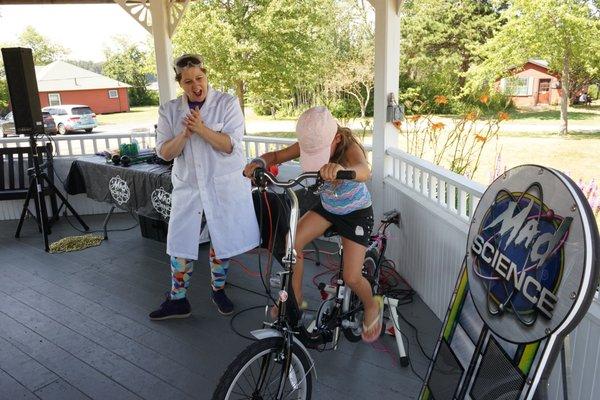 Amethyst Amanda encouraging a young scientist to convert mechanical energy into electricity using her leg power!