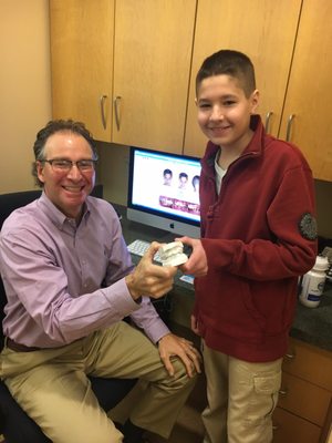 Dr. Margolis is presenting Cameron with the mold of his old teeth.