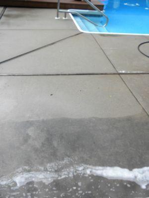 Pool surround before pressure washing (lower portion of photo) and after pressure washing (upper portion of photo)