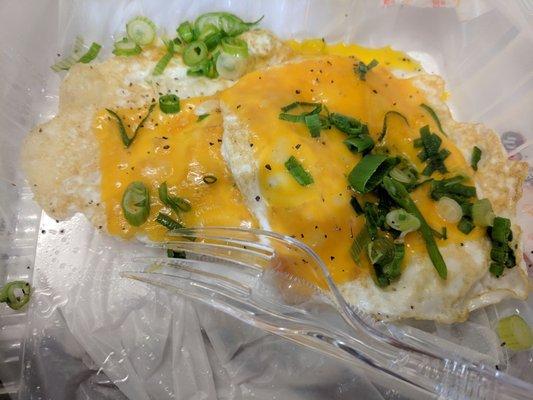 Sunny up eggs (two pictured) topped with cheddar and green onions.