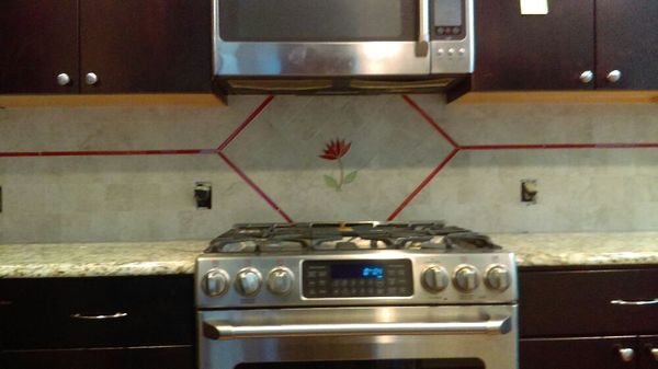 Custom travertine and glass backsplash with raised glass/travertine flower inset