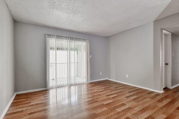 the spacious living room with sliding glass doors and wood flooring