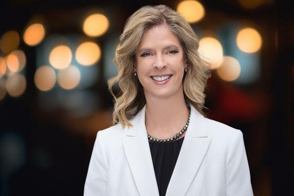 A professional portrait of a smiling woman in a white blazer, captured at our Cincinnati photography studio for personal branding headshots.