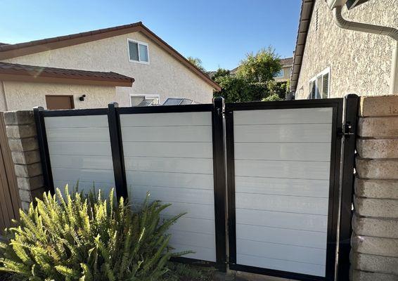 Grey horizontal vinyl fence with a single gate with aluminum frame