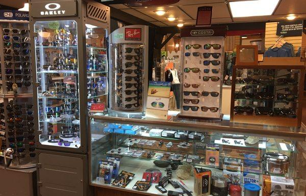 A variety of brand name sunglasses including Ray Ban, Costa, Maui Jim, Oakley, & Optic Nerve