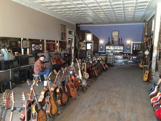 A customer tries out a nice classical guitar among the various guitars in the front room.