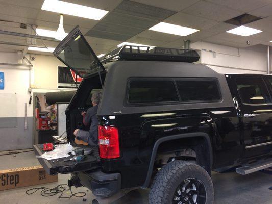 Here's Jon installing an ARE camper shell with an Ascend roof basket and bedliner finish on a new GMC.