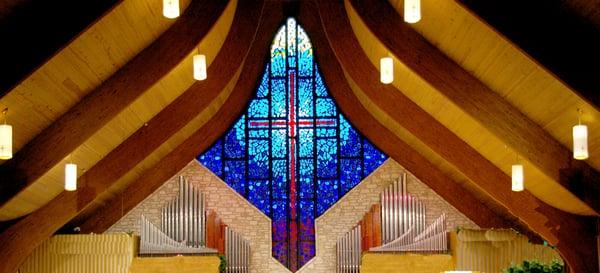 The stained glass cross and organ at the front of Covenant's Sanctuary