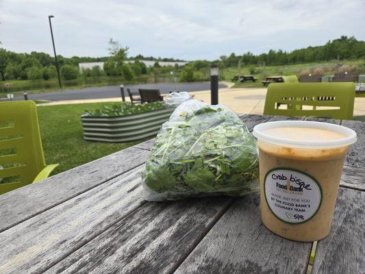 Outdoor seating with some crab bisque and arugula to go for home.