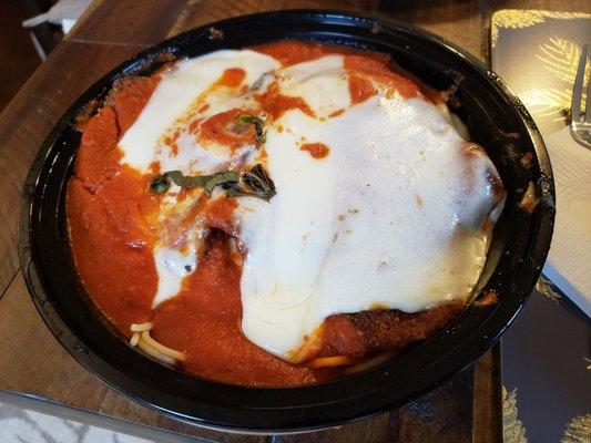 Veal Parmigiana lunch portion takeout topped with spaghetti which was tasty and delicious, but hard to pick up with a fork and knife.