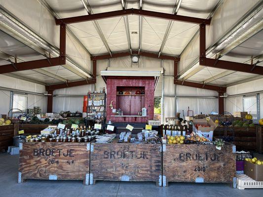 An array of jars of honey, dried fruit packages, jars of olive oil and other products sold inside the red barn.