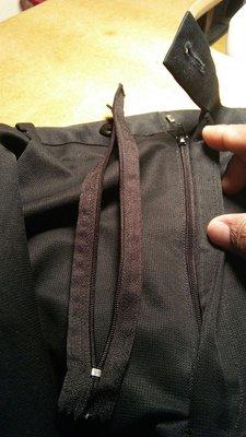 Old zipper taken off and placed on top next to new zipper sewn in on slacks.