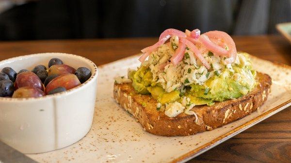 Crab& Avocado Toast: Wild caught blue crab and avocado on top of our whole grain artisan toast with house-pickled red onions.