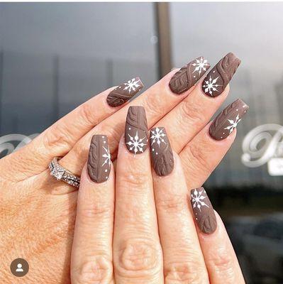 White snowflakes and sweater design on brown nails