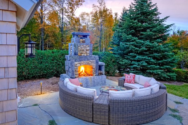 Outdoor fireplace with monolithic granite and soapstone firebox combined with fieldstone.