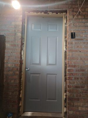 Door 3.  Door left like this. Improperly set, caulking unfinished, no framing around the door.