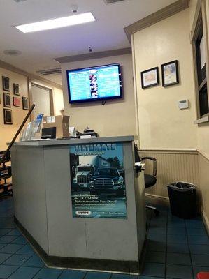 Waiting area with the front desk and one of 3 tv's!