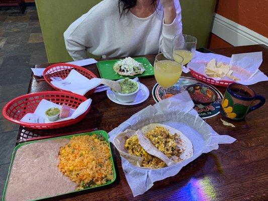 Chorizo and egg tacos and a beef fajita tostada mimosa and chips.