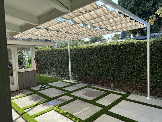 Completed backyard patio with concrete & artificial turf design + overhead sunshade.