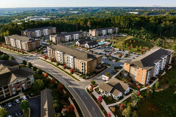 This is an aerial photograph of a large, modern apartment complex nestled among greenery. www.sixcentsmedia.com