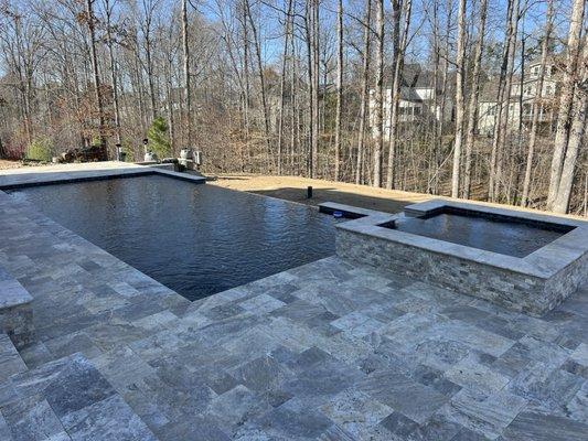 Infinity edge concrete pool, raised spa, silver travertine decking and copping.