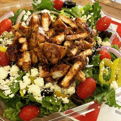 Greek Salad topped with jerk chicken.