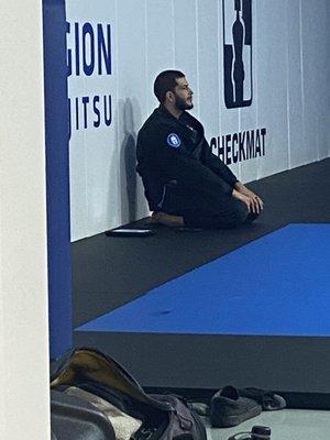 Professor Alex waiting patiently for students to come on the mat