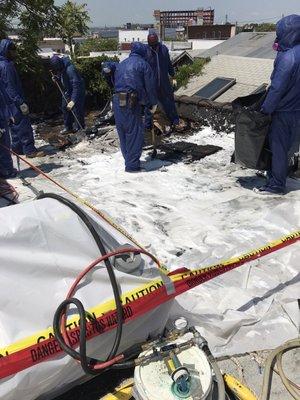 Worker spraying white foam on the roof before removal is started